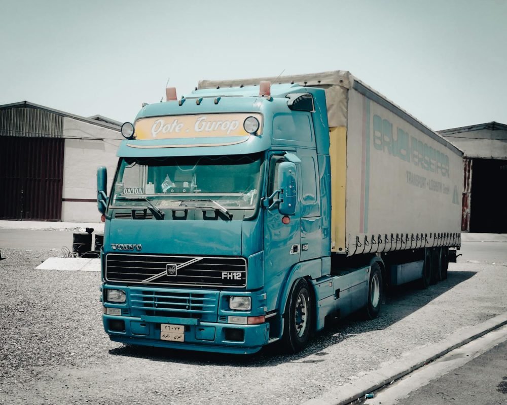 Photo by Esmihel Muhammed Transporte Araque Coslada Madrid - A blue Volvo truck parked outside a warehouse in an industrial area, daytime scene.
