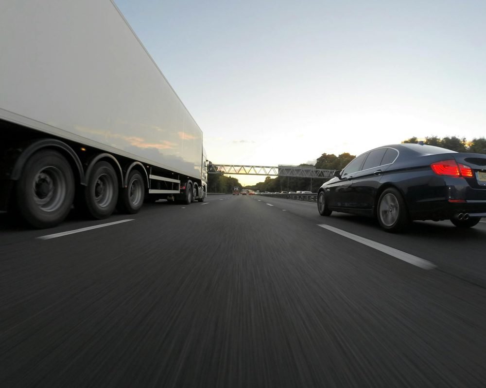 Photo by Mike Bird Transporte Araque Coslada Madrid - Cars and a truck speed along a highway under the clear sky, showcasing transportation dynamics.
